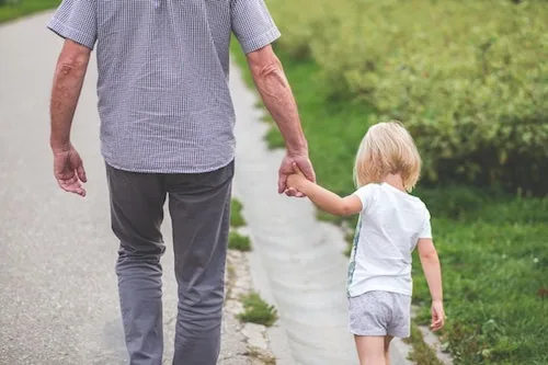 Adult and young child holding hands walking together on a path